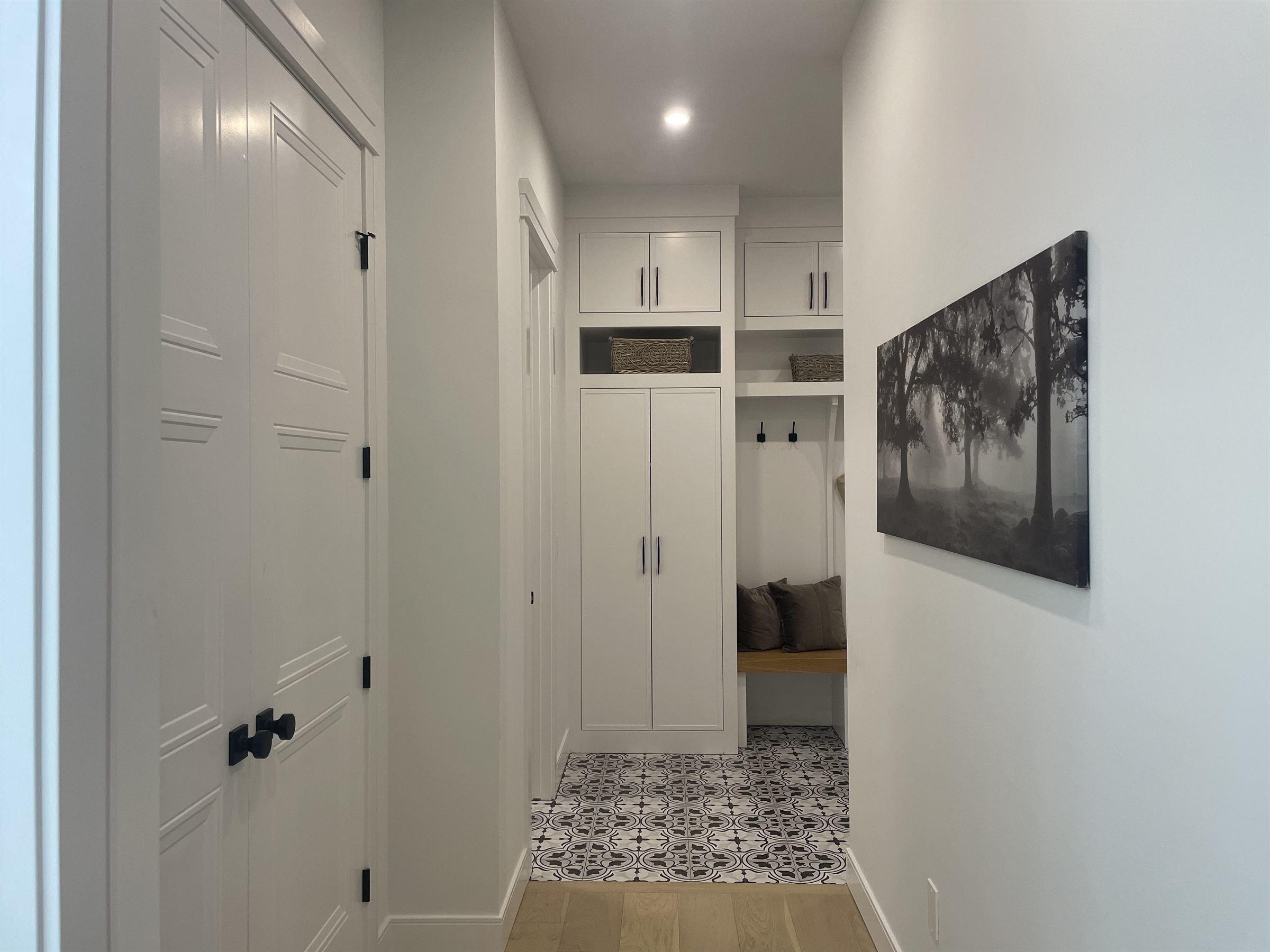 Hallway with framed art and a patterned tile floor