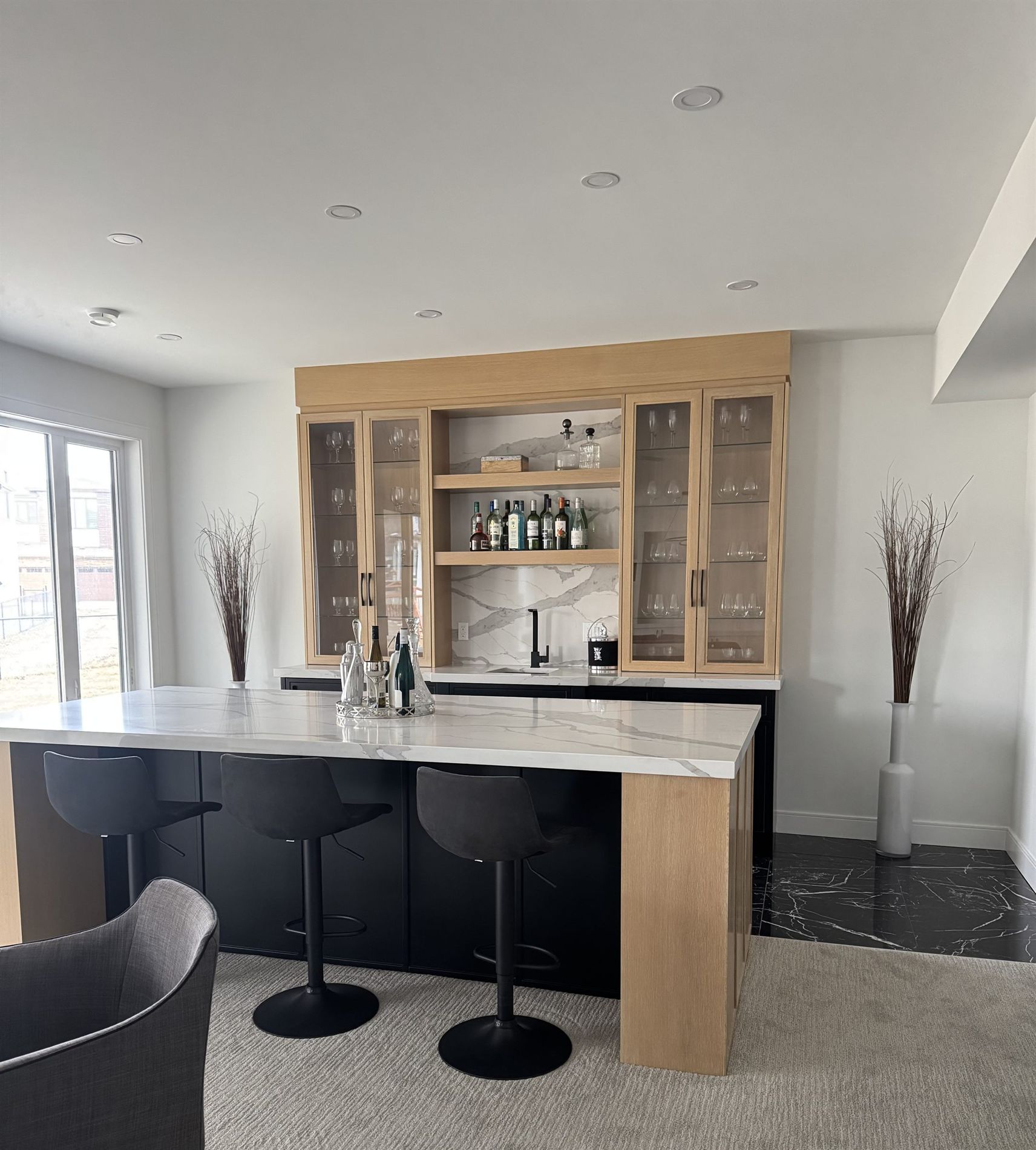 Oak wet bar with glass-front cabinetry and a waterfall marble counter