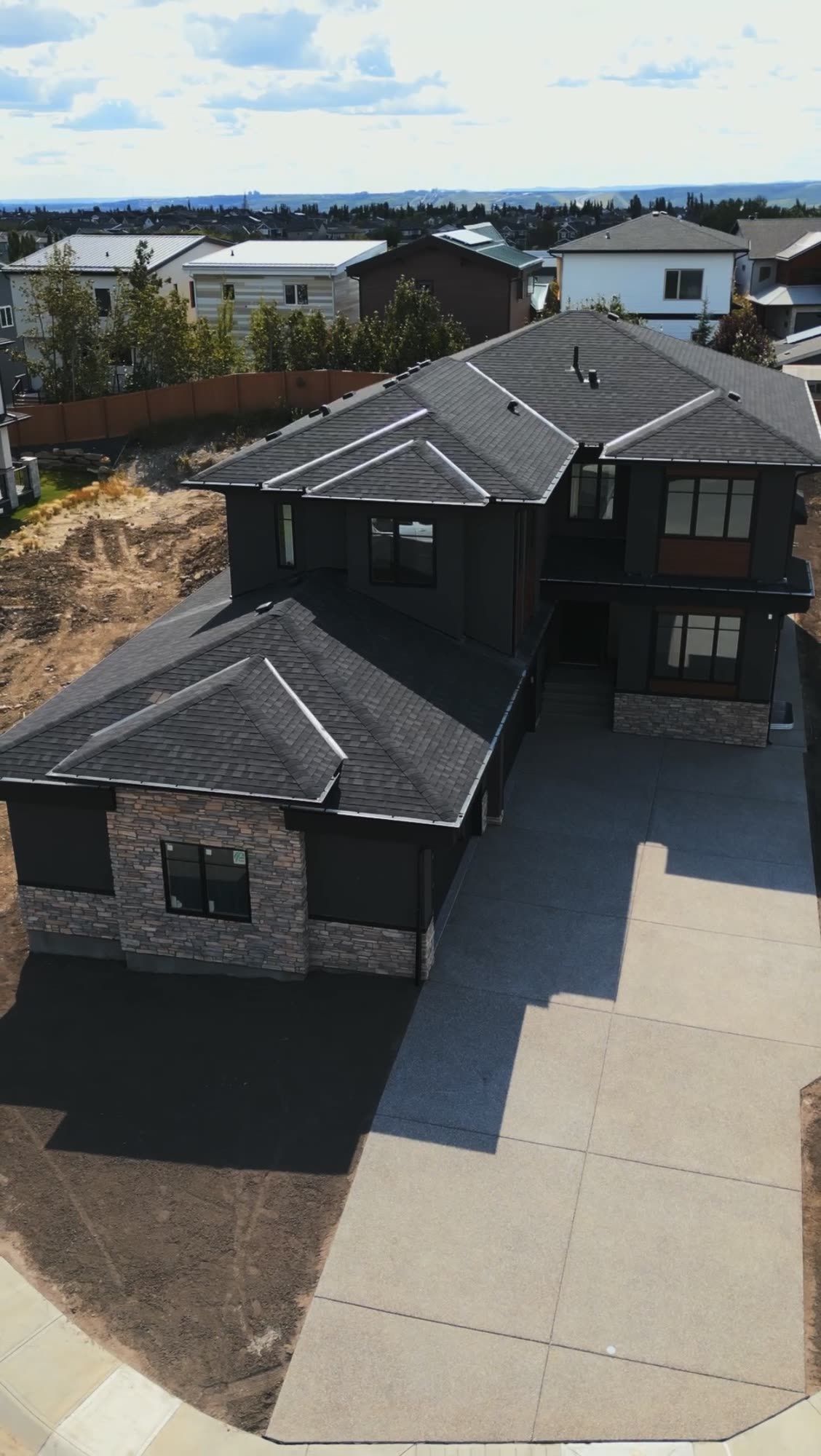 Aerial view over a finished home, its roofline and the new driveway