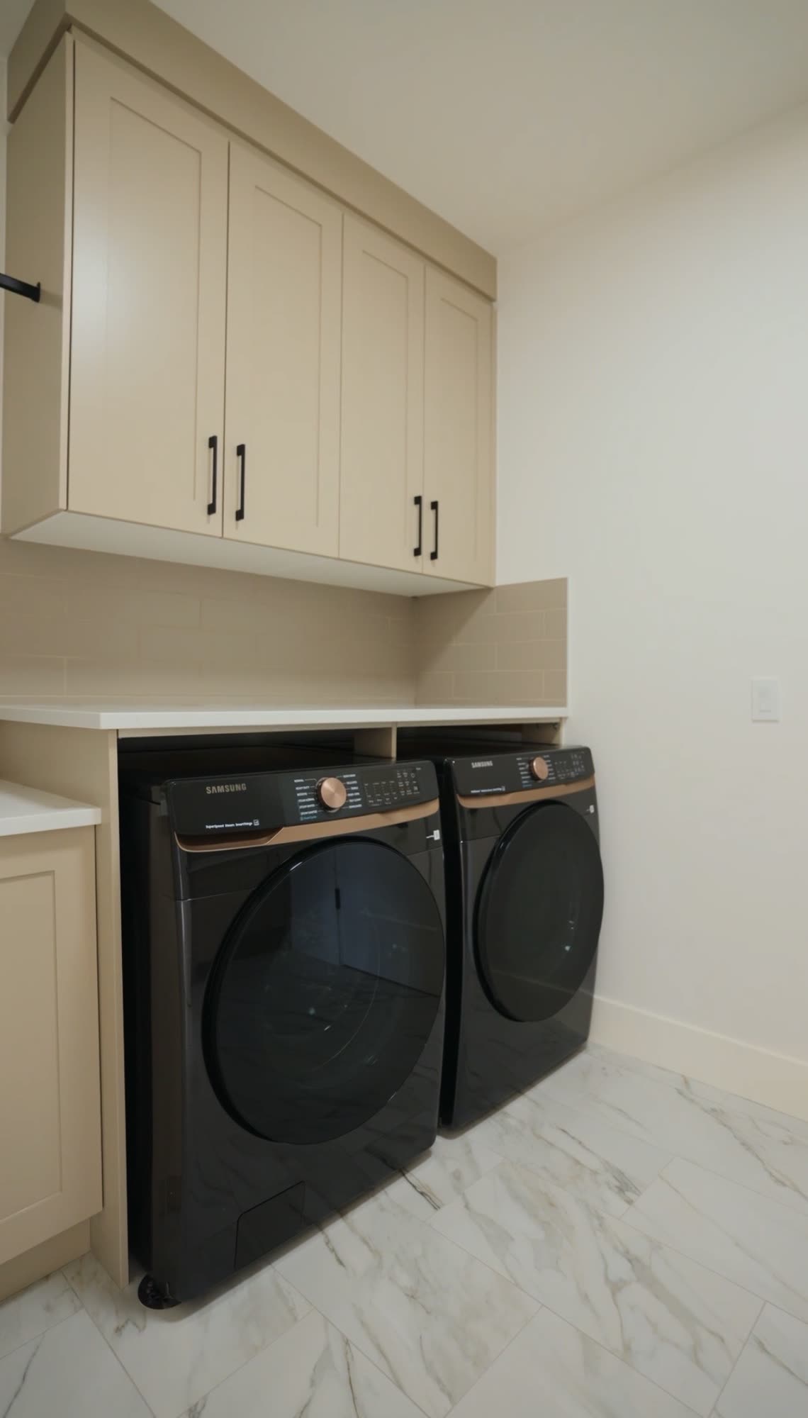 Laundry room with front loading machines under cream cabinetry