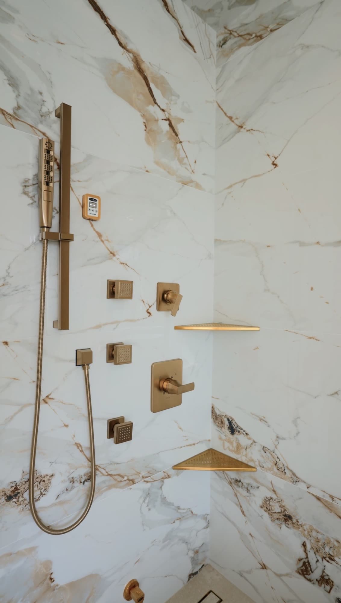 Marble shower wall with brass fixtures and body jets