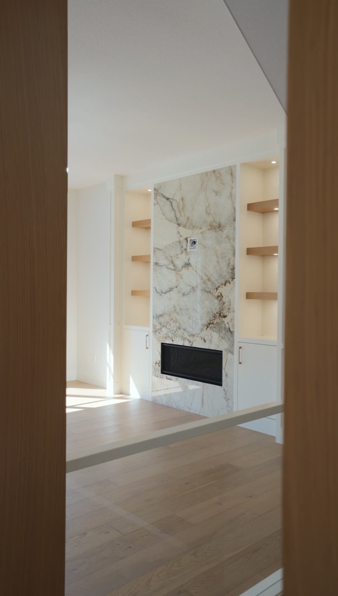 Marble fireplace slab flanked by oak shelving